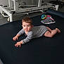 baby, blue_eyes, child, crawling, curious, face, floor, flooring, gray_clothing, gym_equipment, head, indoor, infant, mat, onesie, person, playtime, short_hair, toy, young_child