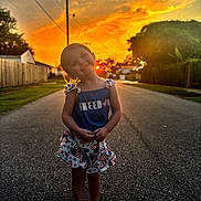 Oakley is registered to the contest to win money with this photo: child, girl, sunset, street, barefoot, smile, dress, patriotic, outdoor, nature, sky, clouds, fence, grass, residential, happy, portrait, face, evening, casual