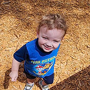 Henry joined the competition — help win amazing prizes! toddler, child, smiling, curly_hair, blue_shirt, paw_patrol, shoes, wood_chips, outdoor, sunlight, shadow, playground, happy, person, casual_clothing, standing, cute, daylight, skin, young_child