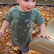 Henry joined the competition — help win amazing prizes! child, toddler, boy, smile, curly_hair, tshirt, shorts, socks, playground, slide, woodchips, fallen_leaves, outdoor, fence, hand, face, cheeky_expression, walking, play, daylight