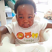 David is registered to the contest to win money with this photo: baby, child, infant, pout, white_shirt, animal_print, peekaboo_text, baby_seat, bear_pattern, indoor, toys, carpet, furniture, cute, portrait, young_child, happy, smiling, person, home