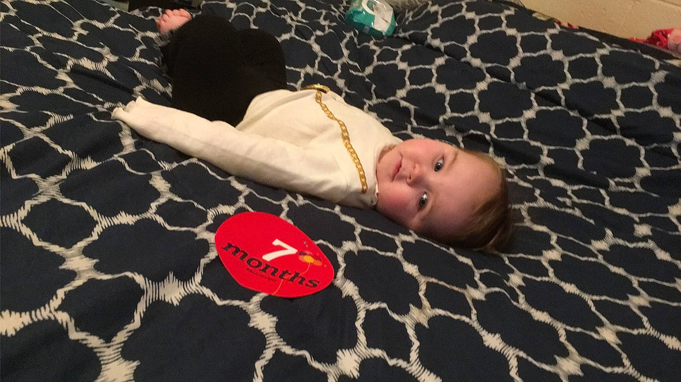 Sarah joined the competition — help win amazing prizes! baby, baby_toddler_clothing, bed, bedding, carmine, child, comfort, floor, flooring, fun, human_leg, leisure, linens, mammal, pattern, person, room, smile, textile, toddler