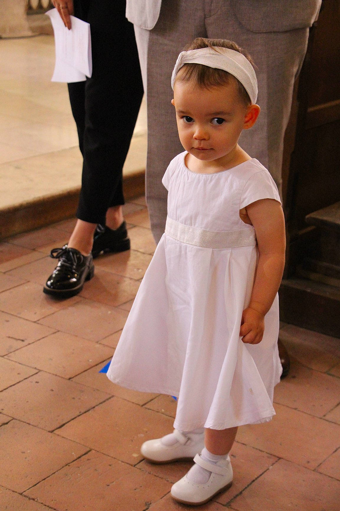 Maëlys participe au concours pour gagner de l'argent avec cette photo : baby, ceremony, child, dress, footwear, formal_wear, gown, person, shoe, smile, toddler, wedding, white