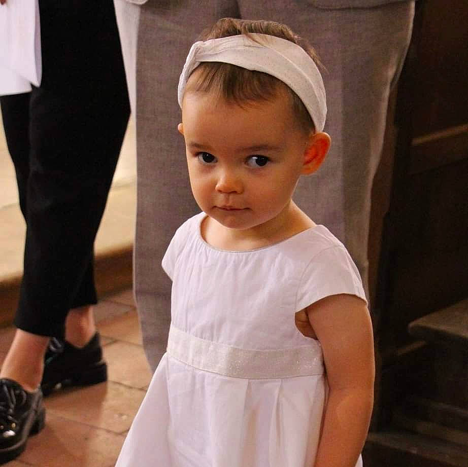 Maëlys a rejoint le concours — aidez-le/la à gagner de superbes lots ! baby, baby_toddler_clothing, ceremony, child, child_model, clothing, dress, fashion_accessory, formal_wear, hair_accessory, headband, headgear, headpiece, neck, person, sleeve, toddler, white
