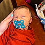 Shawn joined the competition — help win amazing prizes! newborn, baby, pacifier, hand, nail_polish, rust_sweater, wooden_table, sleepy, infant, person, closeup, face, skin, cozy, knitwear, indoor, child, comfort, resting, holding