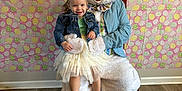 Scarlett joined the competition — help win amazing prizes! child, easter_bunny, costume, dress, denim_jacket, smile, indoor, floor, wood_floor, chair, holiday, easter, background, pattern, pink, yellow, green, white, person, happy