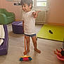 armchair, barefoot, boy, broom, child, doll, floor, furniture, indoor, mat, ottoman, person, playroom, shirt, shoe, shorts, sweeping, toy, window, wood_floor