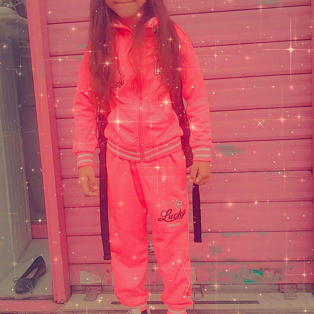 Divna a rejoint le concours — aidez-le/la à gagner de superbes lots ! backpack, casual_clothing, child, concrete_floor, daylight, door, fashion, full_body, girl, long_hair, outdoor, pink_tracksuit, portrait, shutter, smiling, sparkle_filter, standing, urban, white_sneakers, young_person