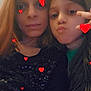 casual_clothing, child, closeup, decorative_stickers, face, female, friendship, fun, hand_gesture, indoor, long_hair, love, peace_sign, person, portrait, pout, red_hearts, selfie, smile, warm_lighting