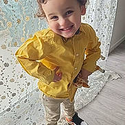 Ilyes participe au concours pour gagner de l'argent avec cette photo : child, toddler, curly_hair, yellow_shirt, smiling, toy, giraffe, indoor, lace_curtain, wooden_floor, sneakers, casual_clothing, playful_pose, happy, person, small_toy, cute, home_interior, fashion, portrait