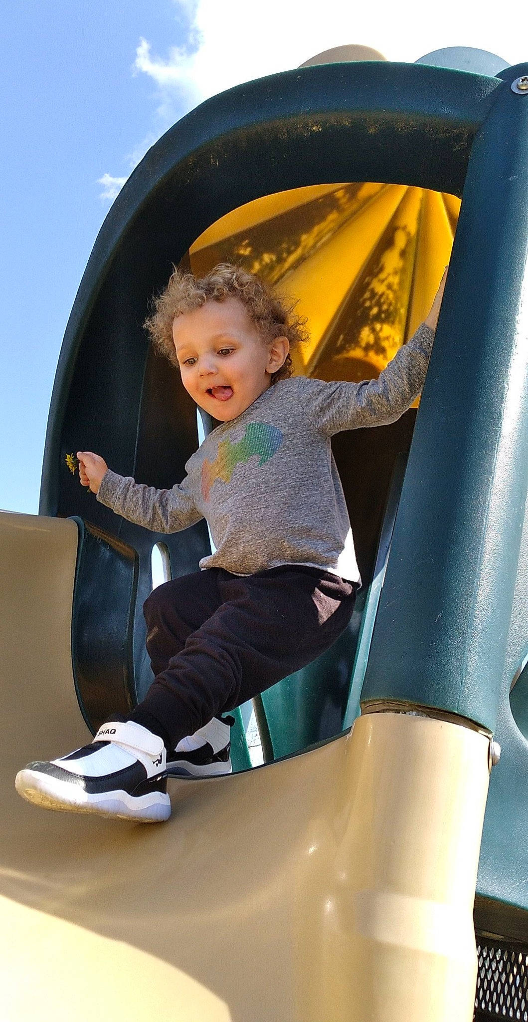 Marcellus is registered to the contest to win money with this photo: child, chute, city, comfort, fun, happy, human_settlement, leisure, outdoor_play_equipment, person, playground, product, public_space, recreation, shoe, sitting, sky, smile, sneakers, standing