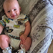 Teegan is registered to the contest to win money with this photo: baby, smiling, onesie, nike, sneakers, blanket, snowflake_pattern, infant, happy, cute, footwear, child, indoors, cozy, clothing, person, sitting, floor, soft, patterned