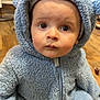 baby, child, blue, hooded_suit, plush, floor, wood, indoor, cute, face, eyes, expression, sitting, warm, cozy, clothing, person, portrait, infant, adorable