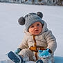 baby, blue_mittens, child, cold_weather, cozy_clothing, curious, fleece, footwear, forest, hat, knit_hat, mittens, nature, outdoor, pom_poms, portrait, sitting, snow, toddler, winter