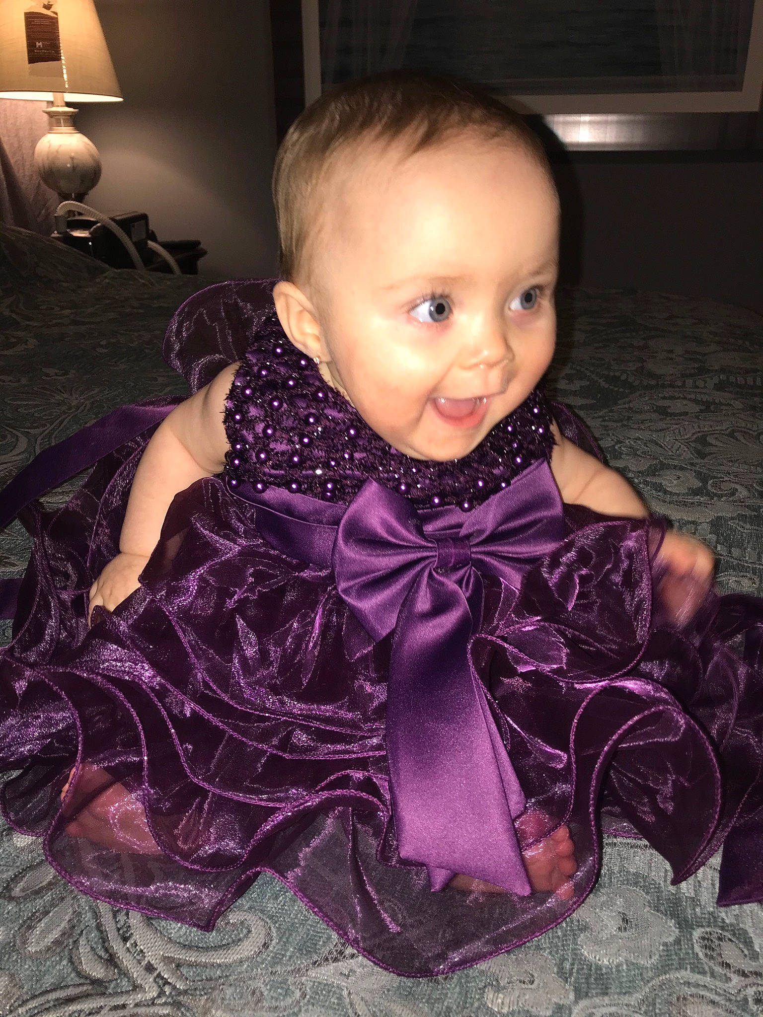Ayvah is registered to the contest to win money with this photo: baby, baby_toddler_clothing, cheek, child, dress, face, formal_wear, fun, head, iris, person, pink, purple, satin, sitting, skin, smile, textile, toddler
