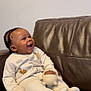 Adel is registered to the contest to win money with this photo: baby, child, smile, happy, braided_hair, onesie, winnie_the_pooh, toy, couch, leather, indoor, person, infant, seated, cozy, cute, playful, young_child, clothing, relaxed