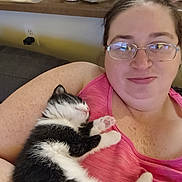 Jellybean joined the competition — help win amazing prizes! person, cat, kitten, sleeping, indoor, smile, glasses, pink_tank_top, black_and_white_cat, couch, arm, cluttered_background, container, kitchen_counter, relaxation, cute, pet, domestic, feline, close_up