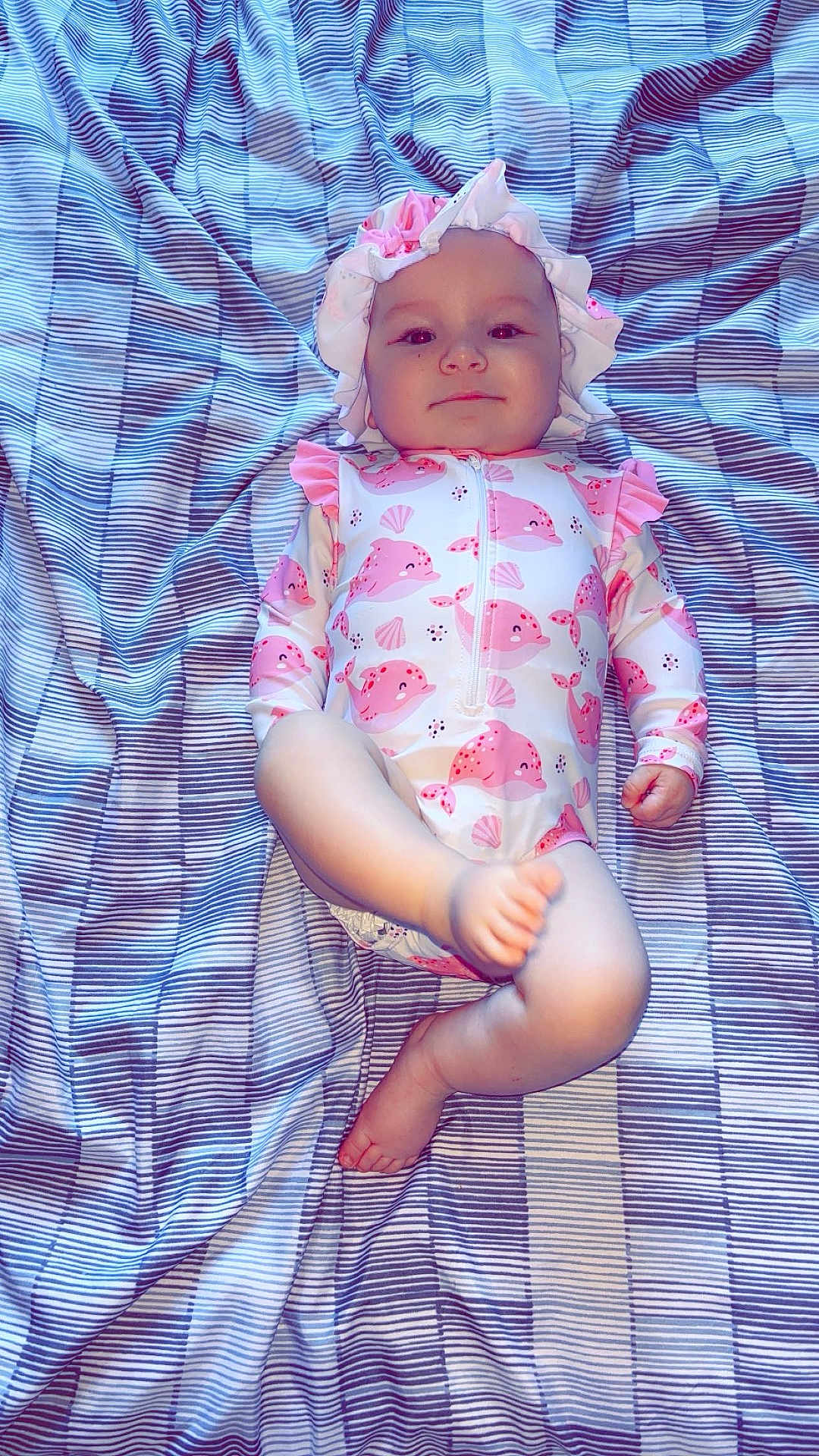 Eva a rejoint le concours — aidez-le/la à gagner de superbes lots ! baby, infant, child, blanket, striped_blanket, clothing, onesie, bonnet, pink, white, dolphin_pattern, seashell_pattern, lying_down, playful, smiling, cute, indoors, soft_lighting, portrait, relaxed