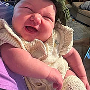 Wilder is registered to the contest to win money with this photo: baby, child, laughing, headband, knitwear, cream_color, arm, person, indoor, living_room, couch, rug, furniture, happy, smile, cute, infant, closeup, cozy, portrait