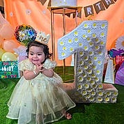 Diana is registered to the contest to win money with this photo: baby, child, birthday, party, dress, crown, balloons, gift, number_one, celebration, smiling, happy, grass, decorations, flower, present, event, festive, cute, indoors