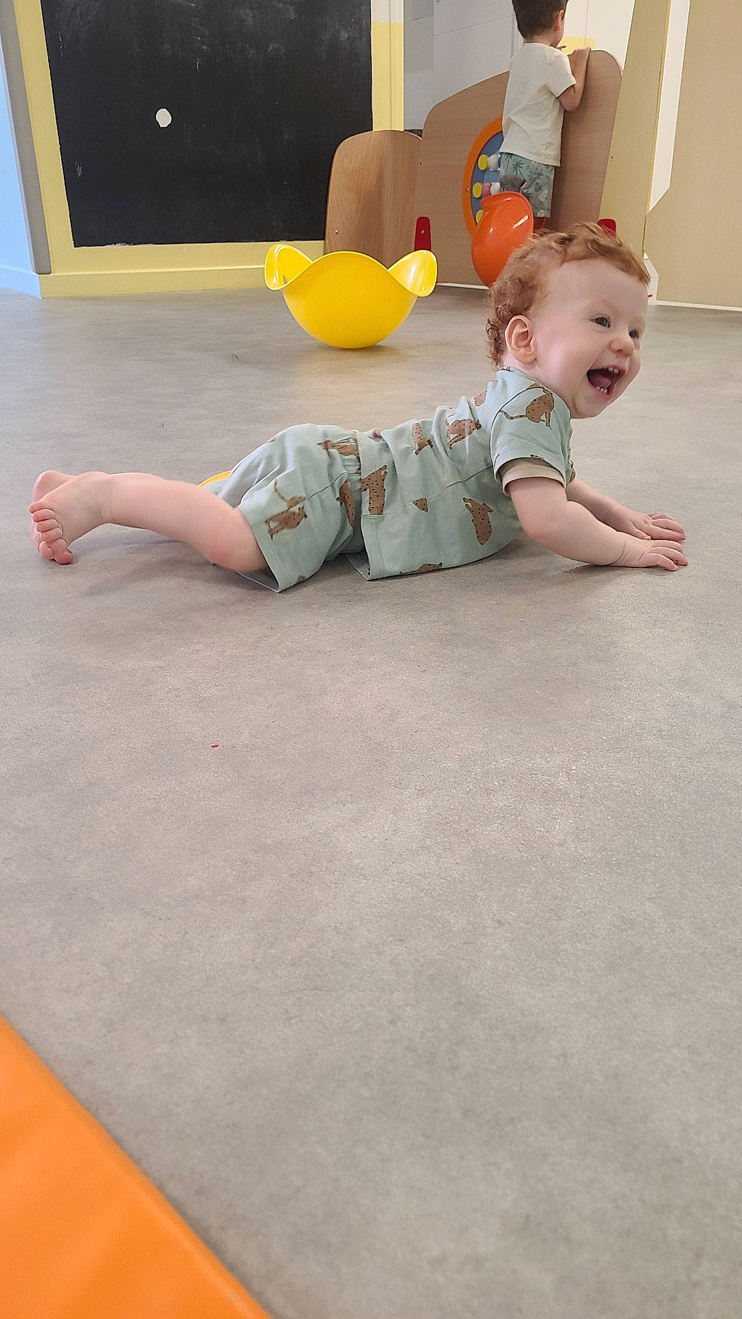 Léon participe au concours pour gagner de l'argent avec cette photo : background, child, child_playing, clothing, curly_hair, floor, furniture, happy, head, indoor, laughing, orange_toy, person, playroom, shirt, shorts, smile, toddler, toy, yellow_toy
