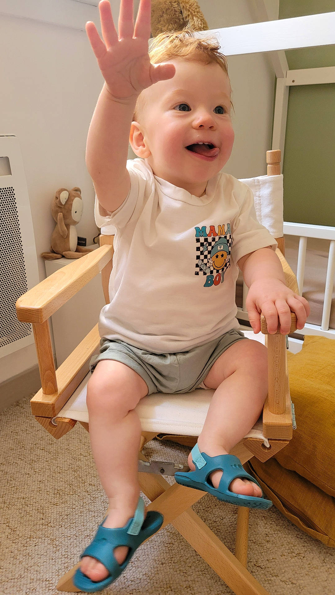 Léon a rejoint le concours — aidez-le/la à gagner de superbes lots ! blue_sandals, carpet, casual_clothing, child, curly_hair, furniture, happy, indoor, light, person, playful, reaching_hand, room, shorts, smiling, stuffed_bear, toddler, tongue_out, white_tshirt, wooden_chair