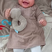 Lou a rejoint le concours — aidez-le/la à gagner de superbes lots ! baby, infant, smiling, plush_toy, blanket, headband, leopard_print, tights, dress, footwear, happy, sitting, indoors, child, cute, person, soft_toy, fabric, pattern, floor