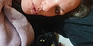 Nala is registered to the contest to win money with this photo: person, cat, black_cat, yellow_eyes, blanket, face, pout, closeup, indoor, cozy, snuggling, pet, fur, relaxed, human, animal, portrait, bed, comfort, expression