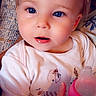 baby, baby_bottle, blanket, blue_eyes, bottle, child, close_up, clothing, couch, face, indoors, infant, onesie, pink, portrait, sitting, smiling, spring, text_overlay, wide_eyed