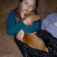 Karlina joined the competition — help win amazing prizes! child, girl, dog, couch, blanket, home, pet, hugging, brown, long_hair, casual_clothing, indoor, cozy, furniture, portrait, cute, animal, friendship, relaxation, comfort