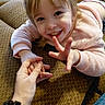 Olivia joined the competition — help win amazing prizes! brown_fabric, casual_clothing, child, couch, counting, face, fingers, hand, happy, holding_hands, home, human, indoor, interaction, person, pink_sweater, playful, smile, toddler, young_child