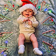 Rowan is registered to the contest to win money with this photo: baby, infant, santa_hat, candy_cane, christmas_lights, holiday, smiling, lying_down, blanket, socks, festive, cute, celebration, happy, child, christmas, soft_texture, seasonal, holiday_decor, festivity