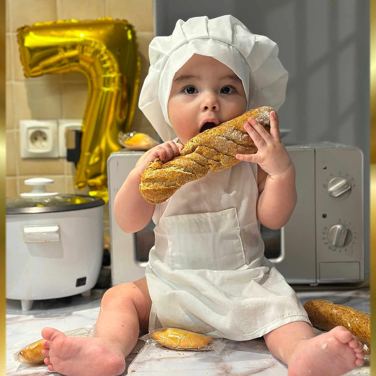 Taylor Ramos a rejoint le concours — aidez-le/la à gagner de superbes lots ! baby, child, chef_hat, apron, bread, baguette, kitchen, countertop, gold_balloon, number_7, rice_cooker, microwave, tile_wall, barefoot, sitting, food, cute, portrait, indoor, playful