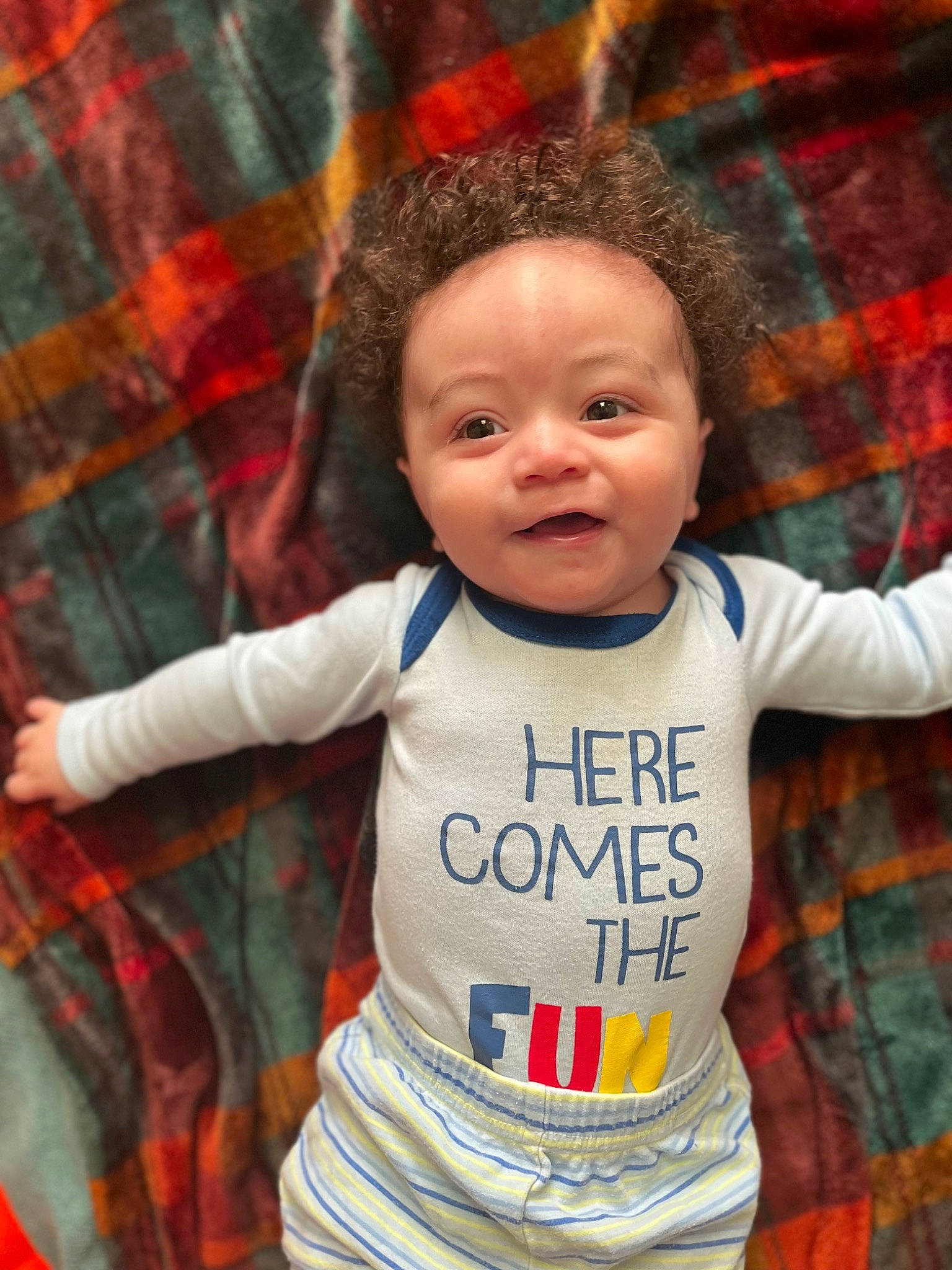 Jakari is registered to the contest to win money with this photo: baby, baby_toddler_clothing, cheek, chin, eye, face, facial_expression, hairstyle, hand, happy, head, iris, lip, person, plaid, skin, sleeve, smile, tartan, textile