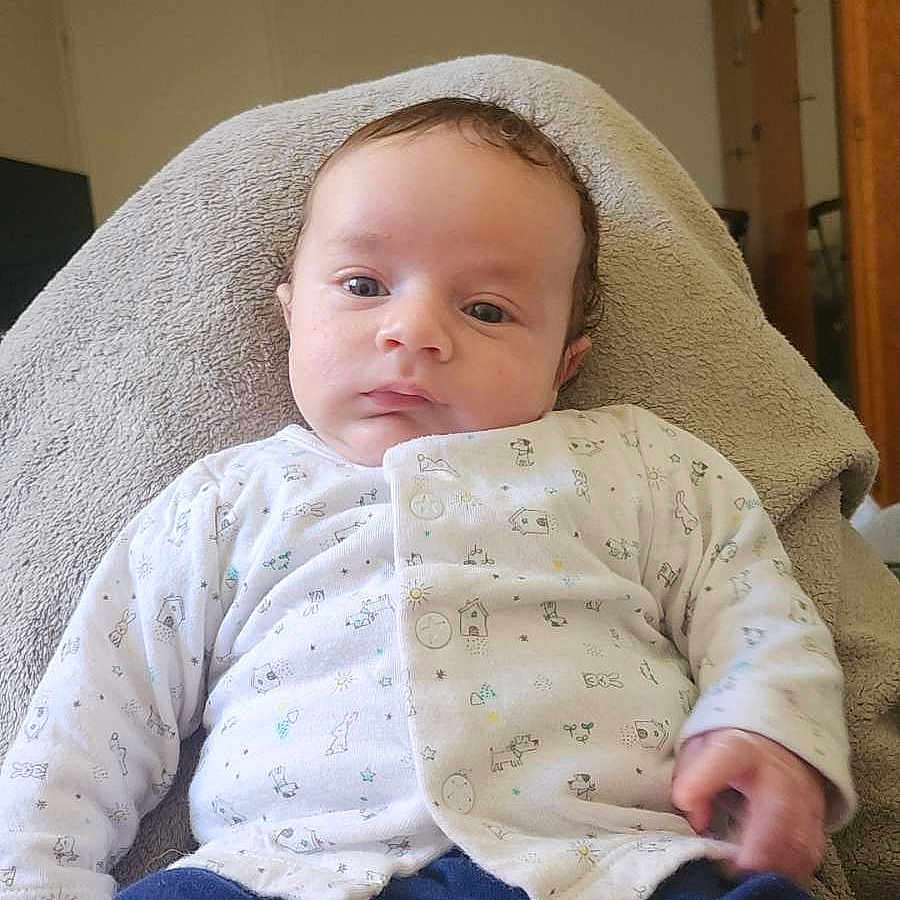 Kenzyo a rejoint le concours — aidez-le/la à gagner de superbes lots ! baby, blanket, blue_pants, calm, child, clothing, cute, face, furniture, home, indoor, infant, pacifier, patterned_clothing, person, relaxed, sitting, soft, white_top, young