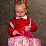 Paisley is registered to the contest to win money with this photo: toddler, child, curly_hair, pigtails, red_sweater, pink_watch, pink_bag, unicorn_pattern, rainbow_pattern, indoor, neutral_background, person, cute, young_child, fashion_accessory, holding, portrait, focus, small_hand, playful