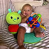 Kohen is registered to the contest to win money with this photo: baby, bed, child, colorful, comfort, cute, diaper, green, happy, indoor, infant, pillow, playful, plush, sitting, smile, soft, striped, toy, young