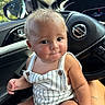 baby, child, infant, person, car_interior, steering_wheel, nissan_logo, window, greenery, romper, striped_clothing, skin, hair, face, eyes, hand, lap, seat, casual, portrait