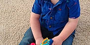 Axel joined the competition — help win amazing prizes! toddler, child, toy, carpet, blue_shirt, jeans, socks, indoor, play, cute, young_child, sitting, looking_up, colorful, plastic_toy, small_person, casual_clothing, infant, baby, floor