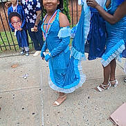 Beautifull is registered to the contest to win money with this photo: child, girl, boy, adult, graduation, gown, tiara, blue_dress, sidewalk, celebration, costume, stuffed_animal, fence, brick_wall, person, outdoor, happy, smile, footwear, event