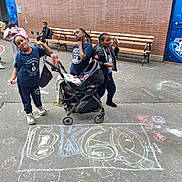 Queen is registered to the contest to win money with this photo: children, playground, chalk_drawing, stroller, sidewalk, brick_wall, bench, urban, kids, play, casual_clothing, baby, group, outdoor, fun, smiling, posing, street_art, daylight, friends
