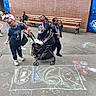 children, playground, chalk_drawing, stroller, sidewalk, brick_wall, bench, urban, kids, play, casual_clothing, baby, group, outdoor, fun, smiling, posing, street_art, daylight, friends
