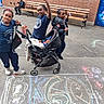 Queen is registered to the contest to win money with this photo: child, children, baby, stroller, chalk_drawing, pavement, schoolyard, bench, brick_wall, playful, posing, outdoor, casual_clothing, smiling, urban, colorful, door_mural, daytime, group, friends
