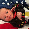 american_flag, baby, black_outfit, clothing, cute, eyes, face, flag, hand, infant, lying_down, newborn, person, portrait, red, skin, small, stars, stripes, white
