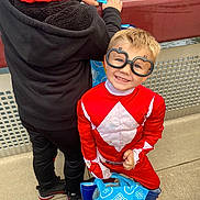 Frankie is registered to the contest to win money with this photo: child, costume, glasses, smile, shopping_bag, alldi_bag, outdoor, water, railing, concrete, black_clothing, red_clothing, short_hair, happy, two_children, playful, daylight, person, standing, casual