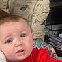 baby, child, infant, face, hand, red_clothing, indoor, furniture, chair, television, pattern, home, curious, closeup, person, skin, expression, seat, couch, living_room