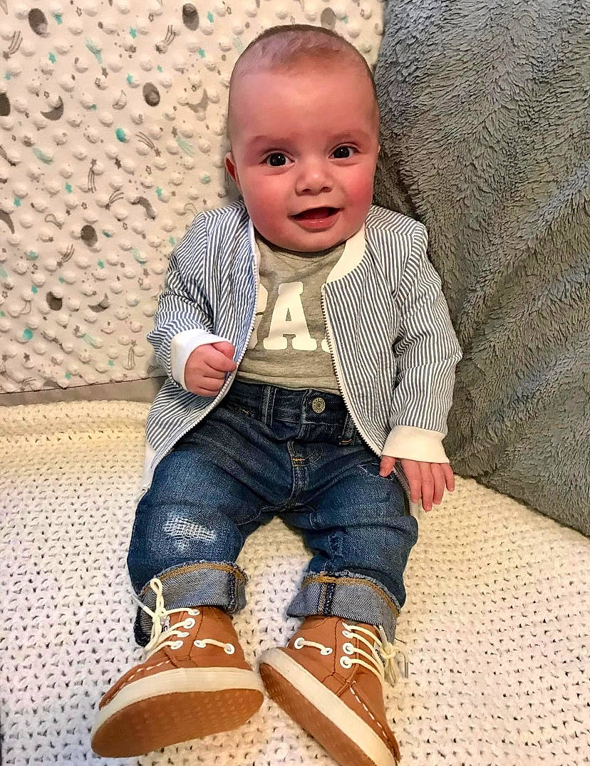Walter is registered to the contest to win money with this photo: arm, baby_toddler_clothing, child, denim, face, flooring, happy, head, human_body, jeans, leg, outerwear, person, skin, sleeve, smile, textile, thigh, toddler, white