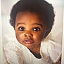 baby, infant, child, afro_hair, white_clothing, portrait, face, eyes, curious, cute, innocence, soft_background, expression, person, closeup, young_child, adorable, skin, head, fashion