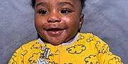 Kwabena joined the competition — help win amazing prizes! baby, child, smile, yellow_onesie, cloud_pattern, happy, infant, portrait, cute, face, expression, clothing, indoor, person, young_child, hands, black_hair, skin, eyes, soft_background