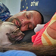 Gwennifer is registered to the contest to win money with this photo: man, dog, sleeping, close_up, face, cozy, indoor, pillow, rest, pet, companion, relaxation, casual_clothing, beard, head, napping, comfort, animal, friendship, bond